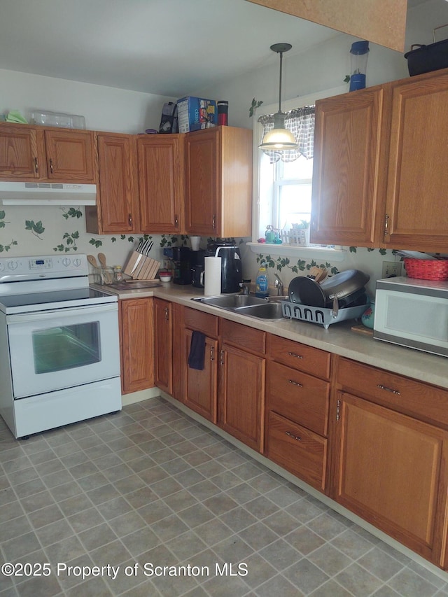 kitchen featuring white appliances, sink, and hanging light fixtures