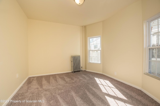 carpeted empty room with radiator, plenty of natural light, and baseboards