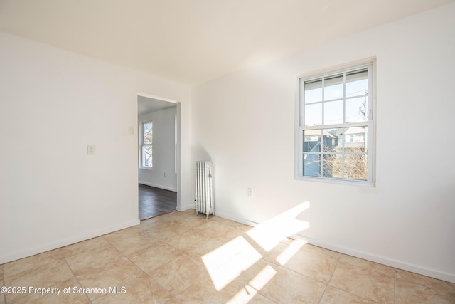 tiled spare room featuring baseboards and radiator heating unit