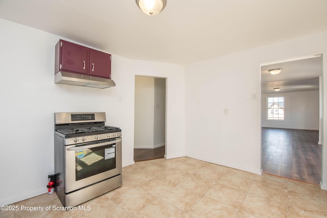 kitchen with baseboards, stainless steel gas range oven, and under cabinet range hood