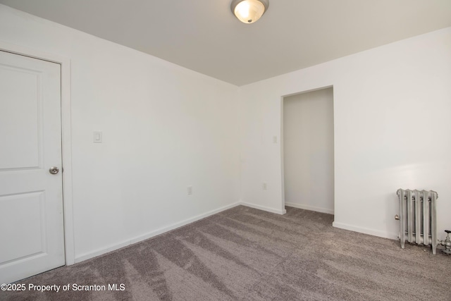 carpeted spare room with radiator and baseboards