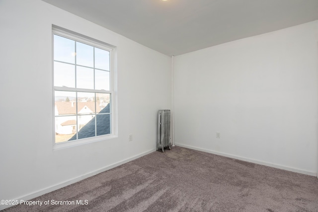 unfurnished room featuring baseboards, carpet floors, and radiator