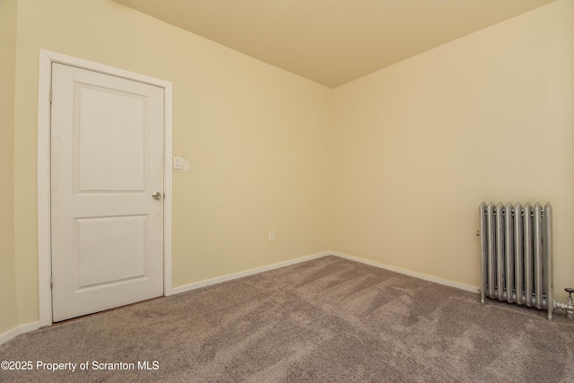 empty room featuring carpet floors, radiator heating unit, and baseboards