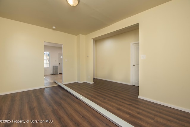 unfurnished room with baseboards and dark wood finished floors