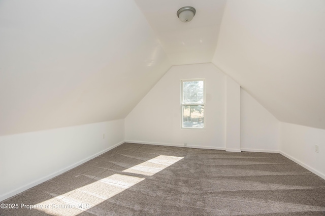 additional living space with carpet flooring, vaulted ceiling, and baseboards