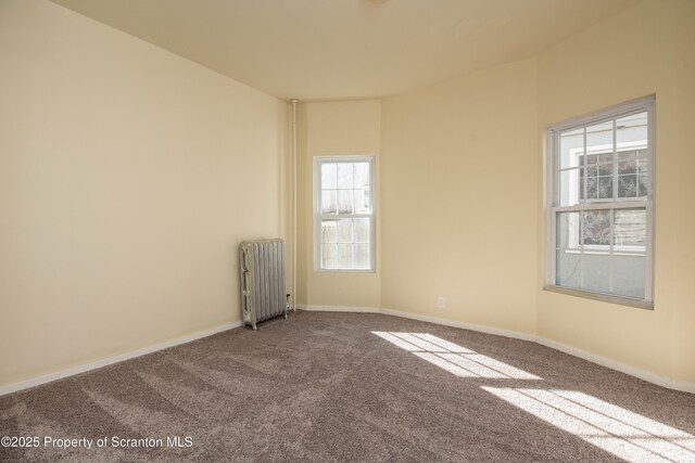 unfurnished room with radiator heating unit, baseboards, and carpet flooring