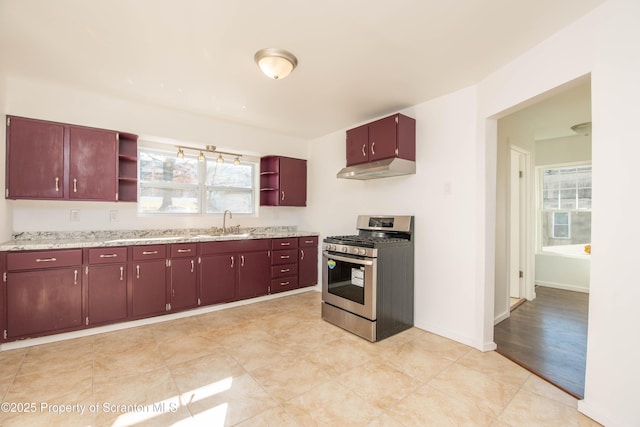 kitchen featuring stainless steel range with gas stovetop, a sink, under cabinet range hood, and open shelves