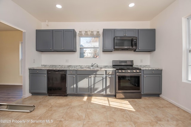 kitchen with appliances with stainless steel finishes, recessed lighting, a sink, and gray cabinetry