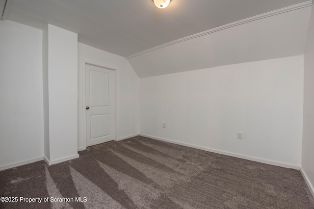 additional living space with lofted ceiling, dark carpet, and baseboards