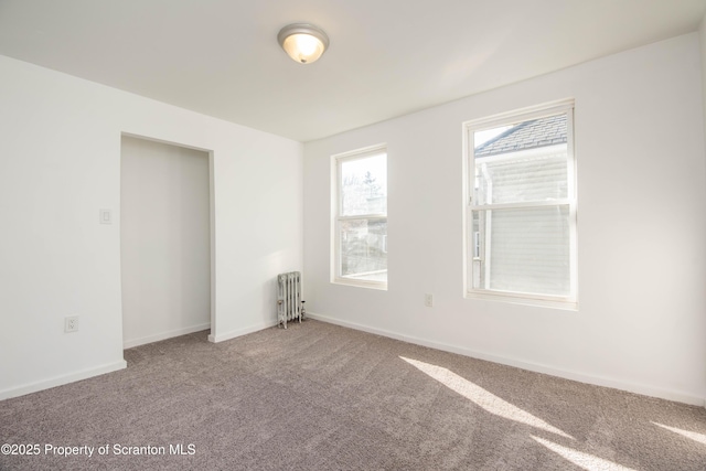 carpeted empty room featuring radiator heating unit and baseboards