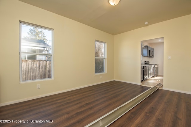 empty room with dark wood-style flooring and baseboards