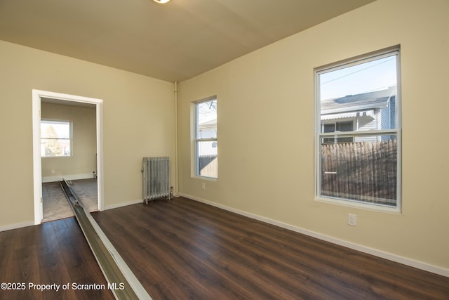 unfurnished room with radiator, baseboards, and dark wood-type flooring