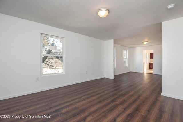 spare room featuring dark wood-style floors and baseboards