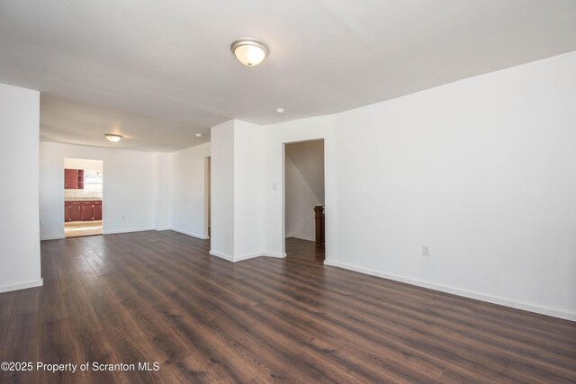 unfurnished room featuring baseboards and dark wood finished floors