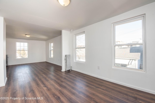 empty room with dark wood-style floors, radiator heating unit, and baseboards