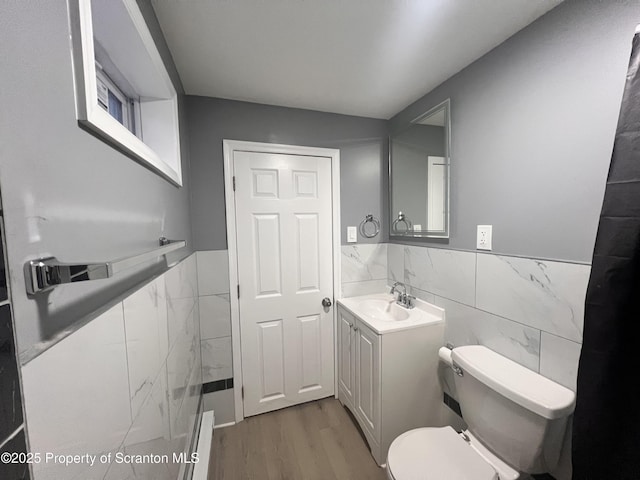 bathroom featuring hardwood / wood-style floors, vanity, toilet, and tile walls