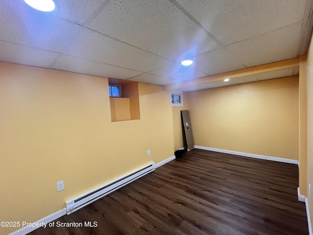 basement featuring a drop ceiling, dark hardwood / wood-style flooring, and baseboard heating