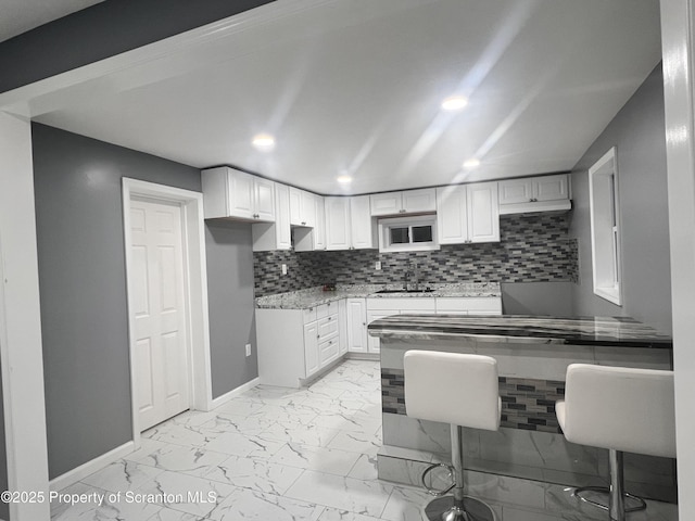 kitchen with white cabinets, tasteful backsplash, and sink