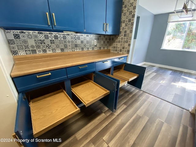 kitchen featuring pendant lighting, backsplash, dark hardwood / wood-style flooring, and blue cabinetry