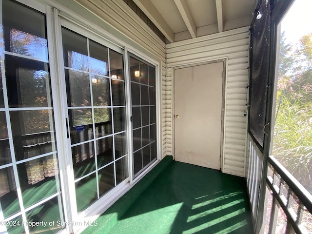 unfurnished sunroom featuring beamed ceiling