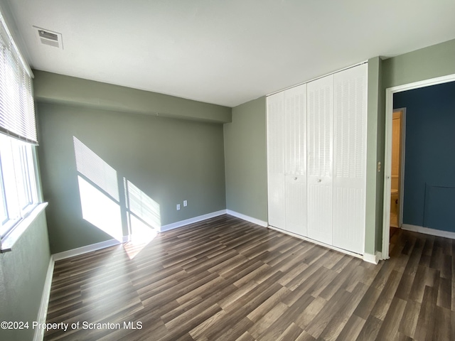 unfurnished bedroom featuring dark hardwood / wood-style floors and a closet