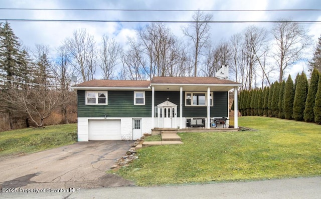 raised ranch with a chimney, a porch, a front yard, a garage, and driveway