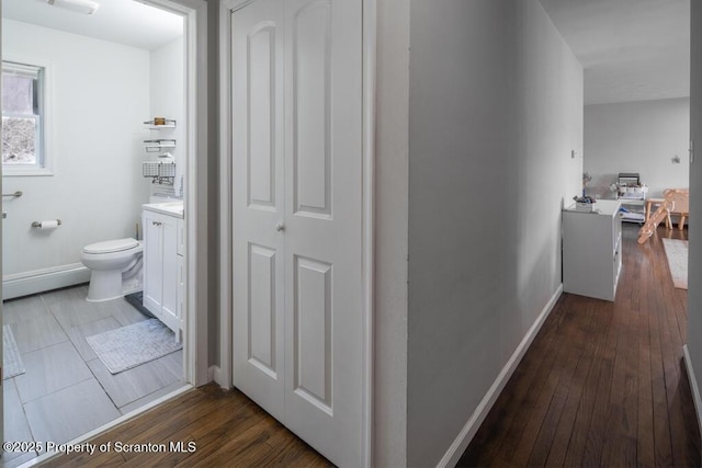 corridor featuring wood finished floors and baseboards