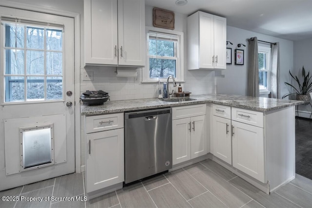 kitchen featuring dishwasher, a peninsula, a sink, and white cabinets