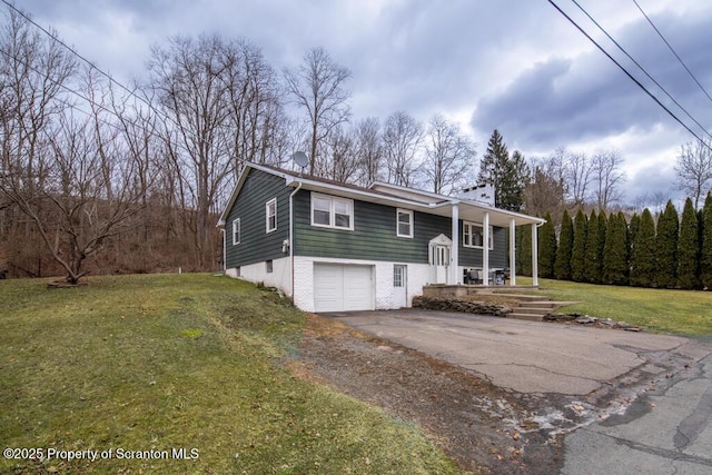 split foyer home featuring aphalt driveway, brick siding, a porch, a front yard, and a garage