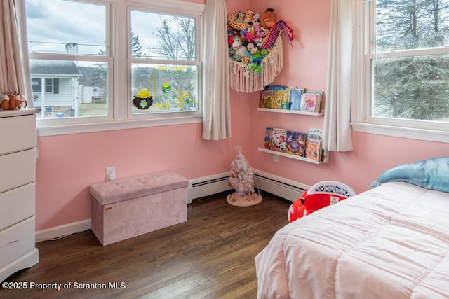 bedroom featuring baseboards, multiple windows, baseboard heating, and wood finished floors