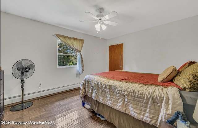 bedroom with baseboard heating, ceiling fan, and wood-type flooring