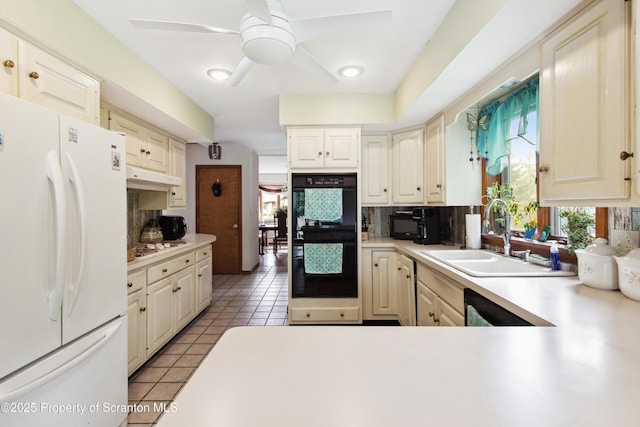 kitchen featuring under cabinet range hood, backsplash, a sink, freestanding refrigerator, and dobule oven black
