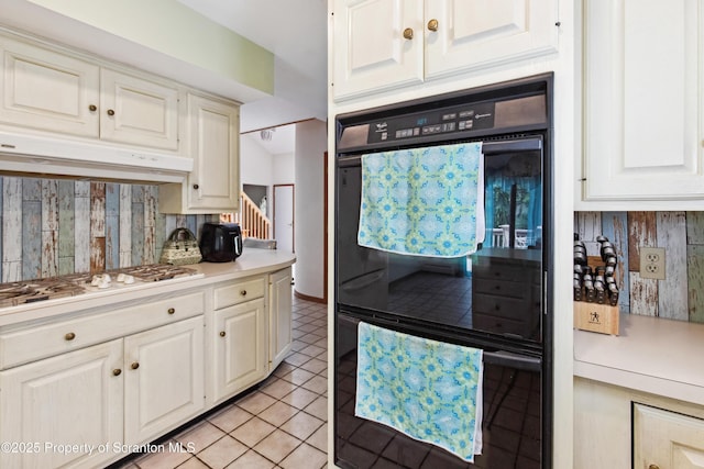 kitchen featuring light countertops, tasteful backsplash, under cabinet range hood, white gas stovetop, and light tile patterned floors
