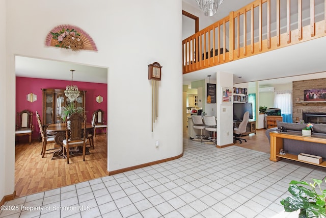 living room with tile patterned flooring, baseboards, a large fireplace, a towering ceiling, and a notable chandelier