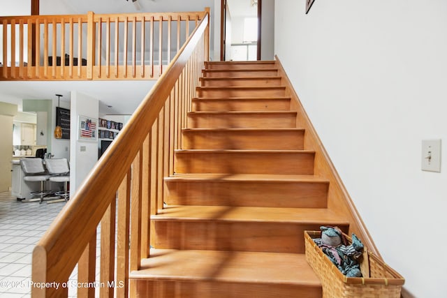 stairway with a towering ceiling and tile patterned flooring