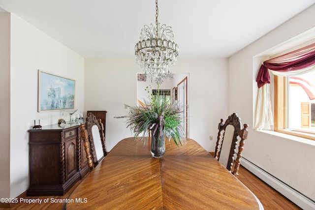 dining space featuring a baseboard radiator, wood finished floors, and an inviting chandelier
