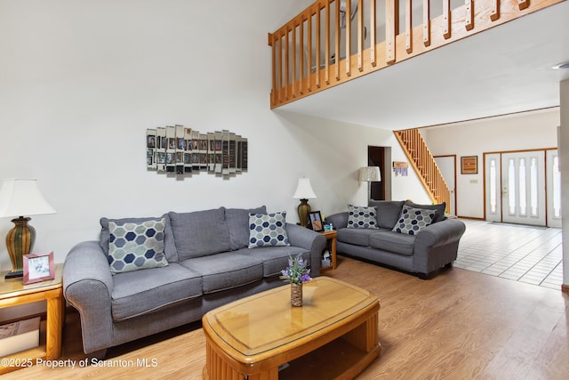 living area with stairs, a high ceiling, and wood finished floors