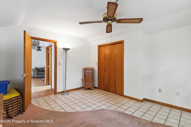 unfurnished bedroom featuring light colored carpet, vaulted ceiling, a closet, and light tile patterned floors