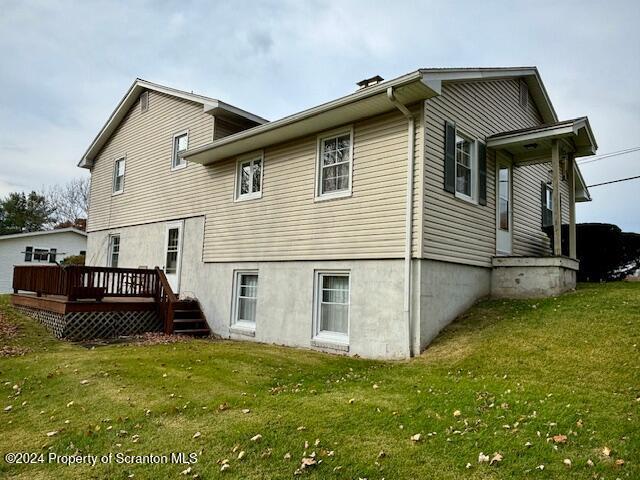 back of property with a lawn and a deck