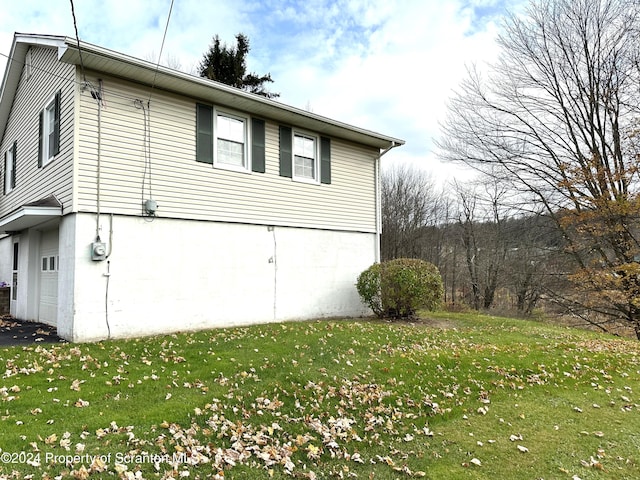 view of side of home featuring a garage and a lawn