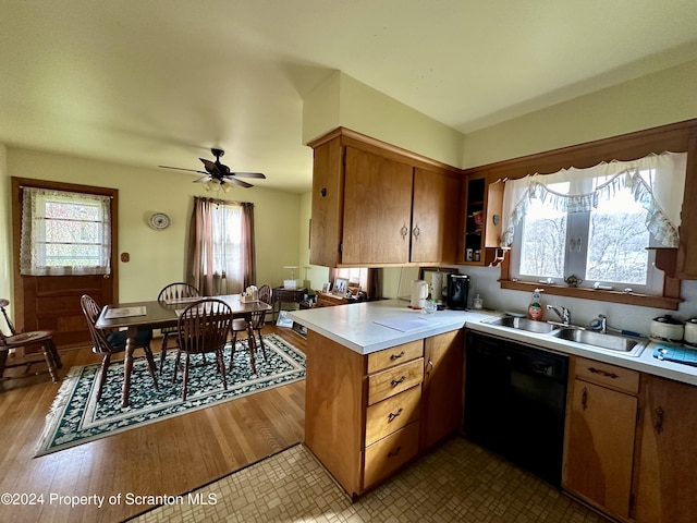 kitchen with black dishwasher, light countertops, brown cabinetry, a sink, and a peninsula