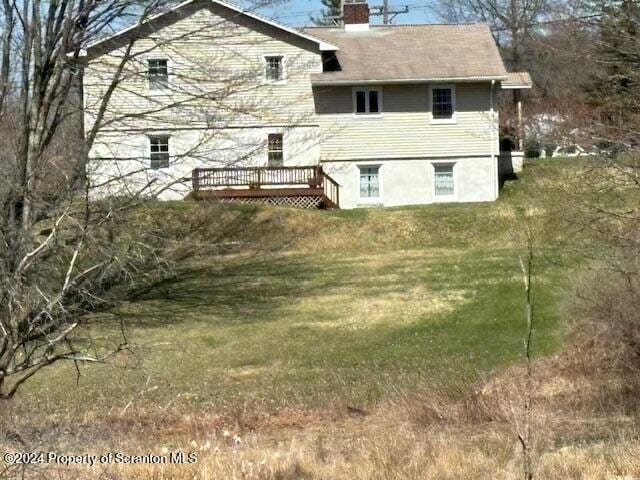 rear view of house with a yard, a chimney, and a wooden deck