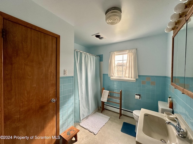 bathroom with a baseboard heating unit, a sink, toilet, and tile walls