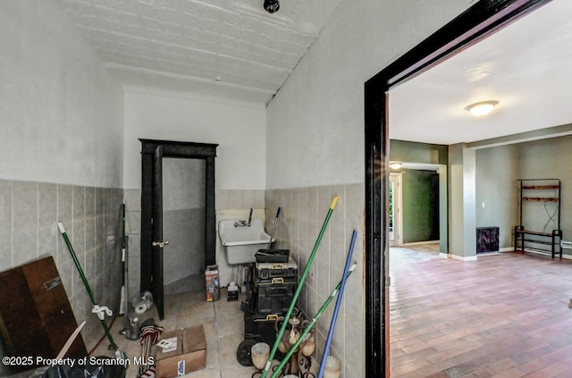 corridor with hardwood / wood-style floors, sink, and tile walls