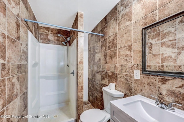 bathroom with toilet, tile walls, vanity, and walk in shower