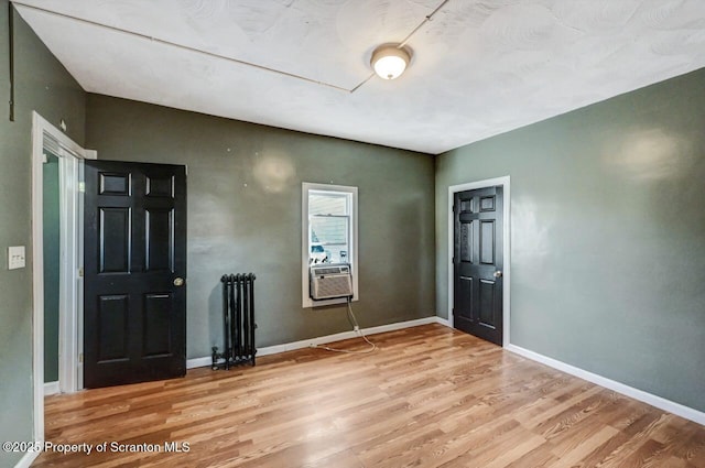 interior space featuring cooling unit, radiator heating unit, and light wood-type flooring