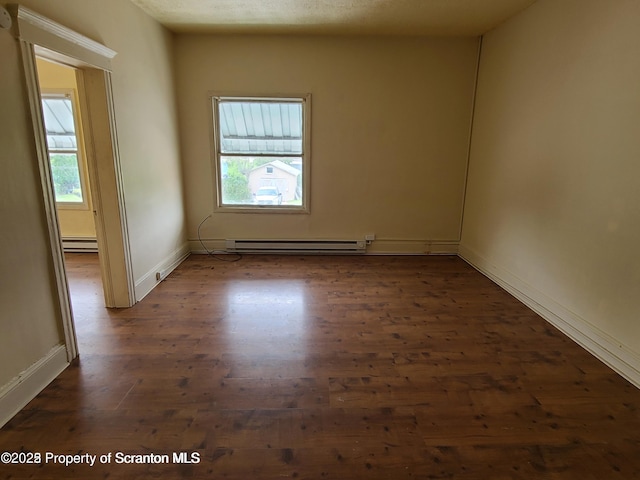 empty room with dark hardwood / wood-style floors and a baseboard heating unit