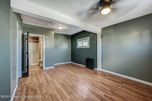 unfurnished room with ceiling fan, radiator, and light wood-type flooring