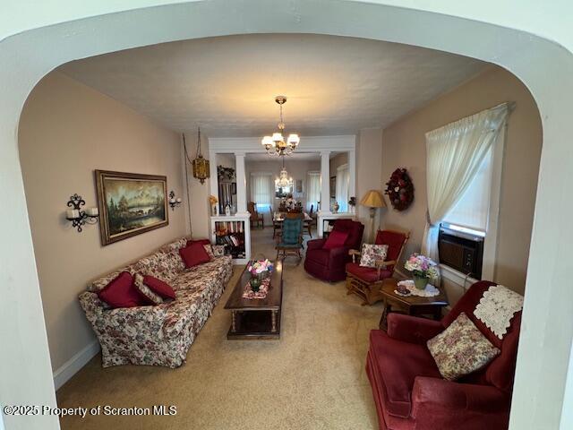 living room with ornate columns, plenty of natural light, carpet flooring, and an inviting chandelier