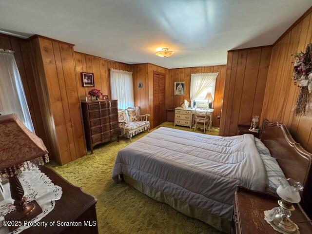 carpeted bedroom with wooden walls